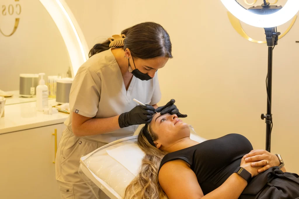 A beauty technician injecting an anti wrinkle treatment to a clients forehead