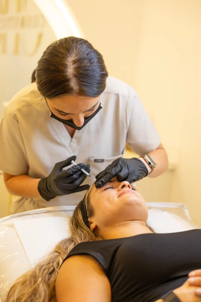 A beauty technician injecting an anti wrinkle treatment to a clients forehead