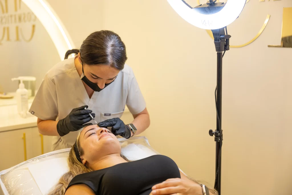 A beauty technician injecting an anti wrinkle treatment to a clients forehead