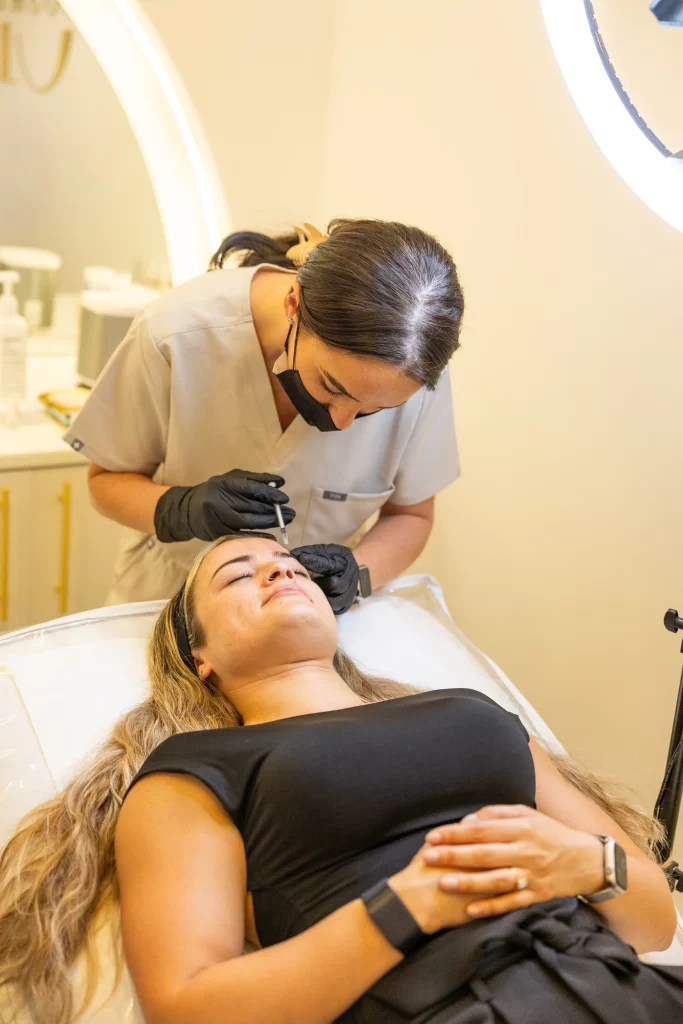 A beauty technician injecting an anti wrinkle treatment to a clients forehead