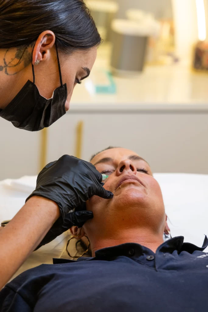 A beauty technician applying a treatment to a clients face